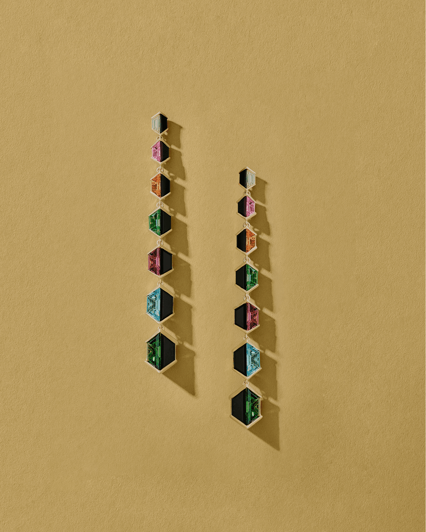 Dangling Apparatta earrings on a mustard paper ground